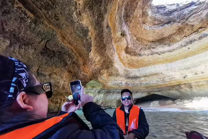 Tourists enjoy a boat trip inside the stunning Benagil caves during an Algarve full-day private tour from Lisbon.