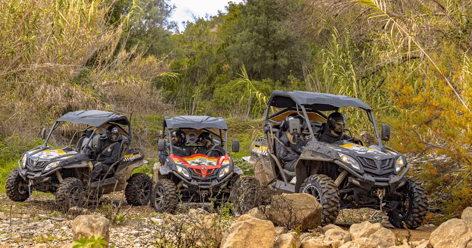 Three Algarve Riders buggies with helmeted drivers tackle rocky off-road trail on guided Algarve buggy safari tour