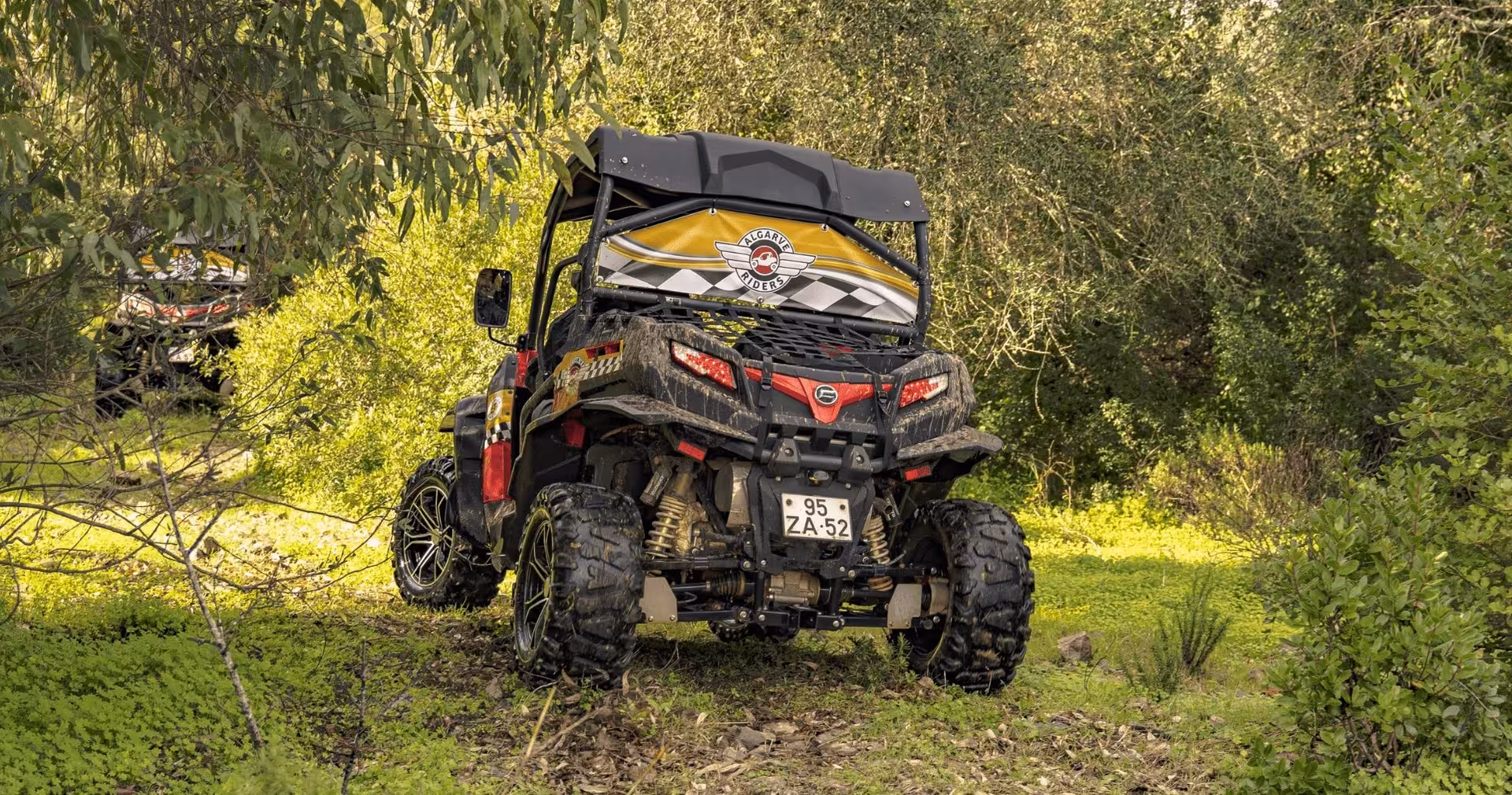 Mud-splattered Algarve Riders buggy parked in lush green forest, showcasing off-road adventure tour through Algarve nature
