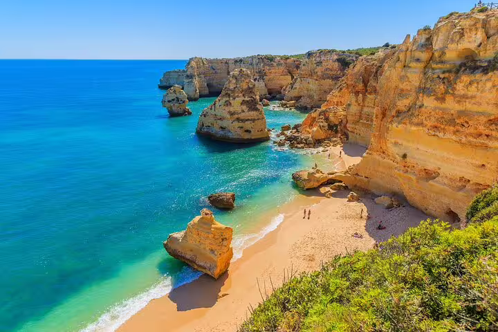 Golden cliffs and pristine beach of Algarve's coastline, featured in private tour from Lisbon with boat experience.