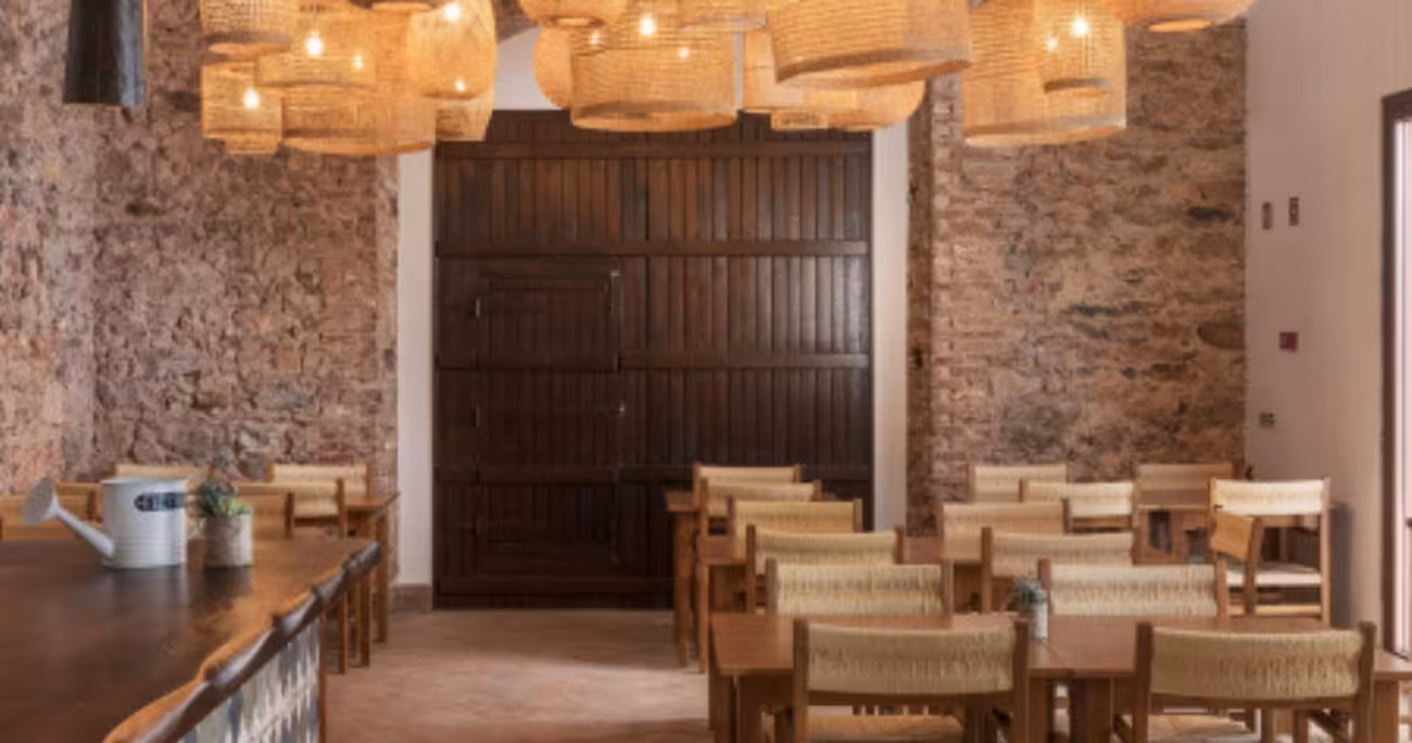 Rustic Algarve dining room with stone walls, wooden tables and woven lamps, featured on The Algarve Heritage Journey tour