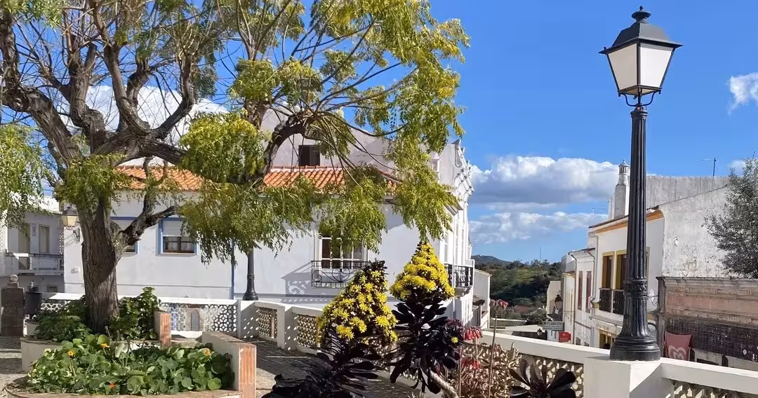 Charming Algarve hilltop square with leafy trees, whitewashed houses and traditional lamppost on a Spirit & Springs walk