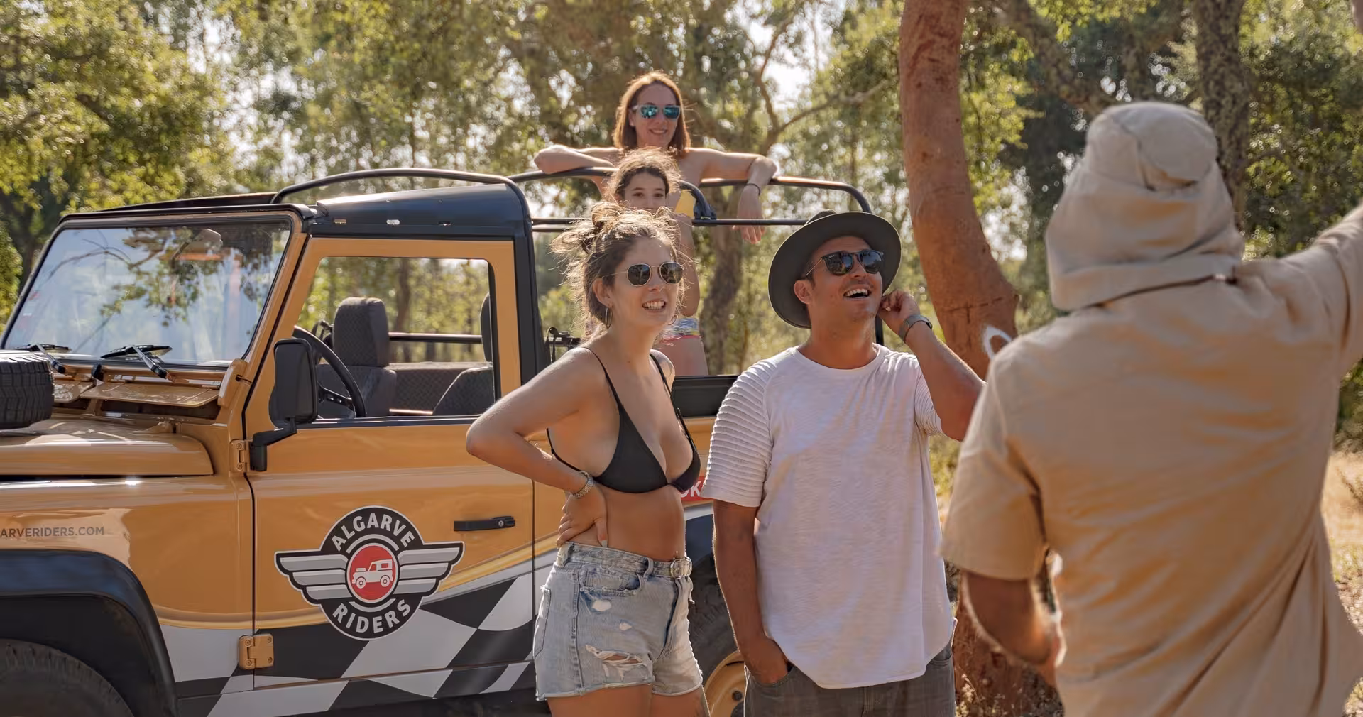Friends on an Algarve Riders jeep safari listen to a local guide amid sunlit cork oak forest on The Crafts & Mountains Journey
