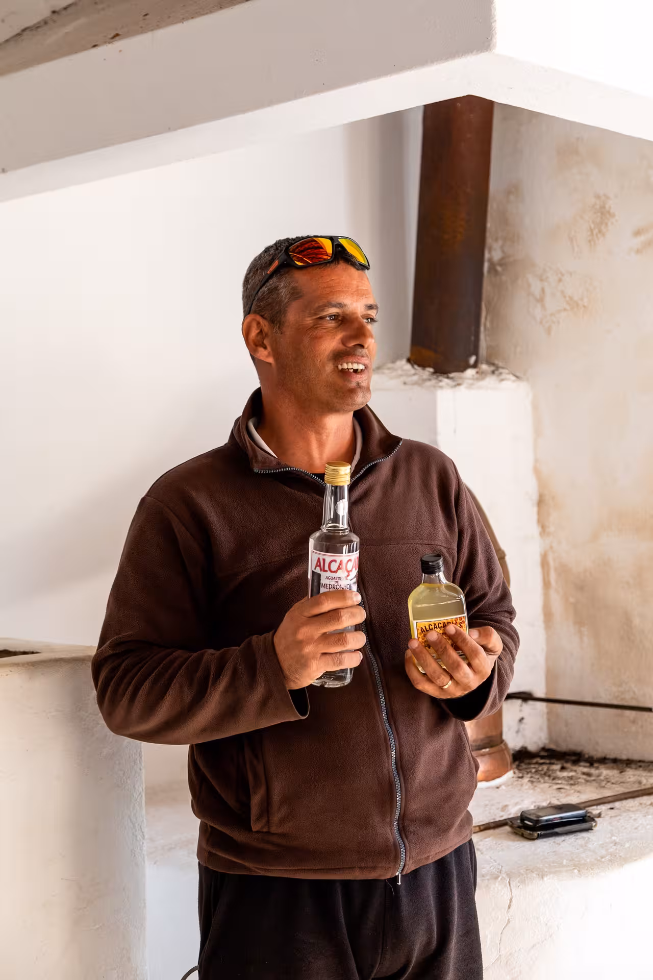 Local guide on Algarve jeep safari presenting traditional Medronho liquor tasting experience inside a rustic distillery stop