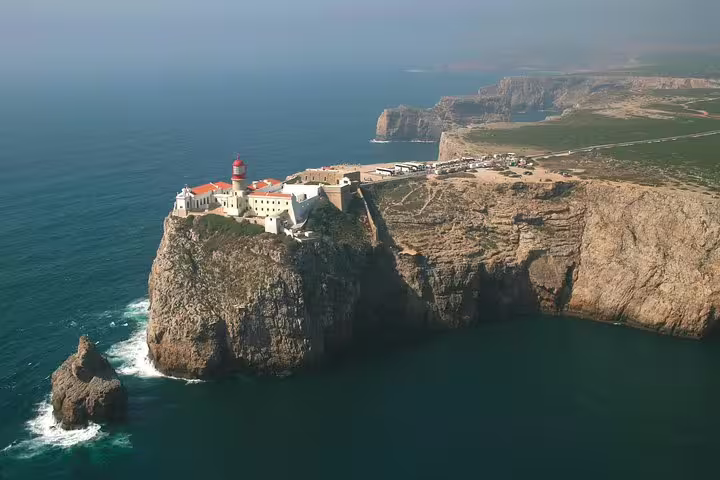 Aerial view of the iconic lighthouse on a rugged Algarve cliff, featured in a 2-day tour from Lisbon.