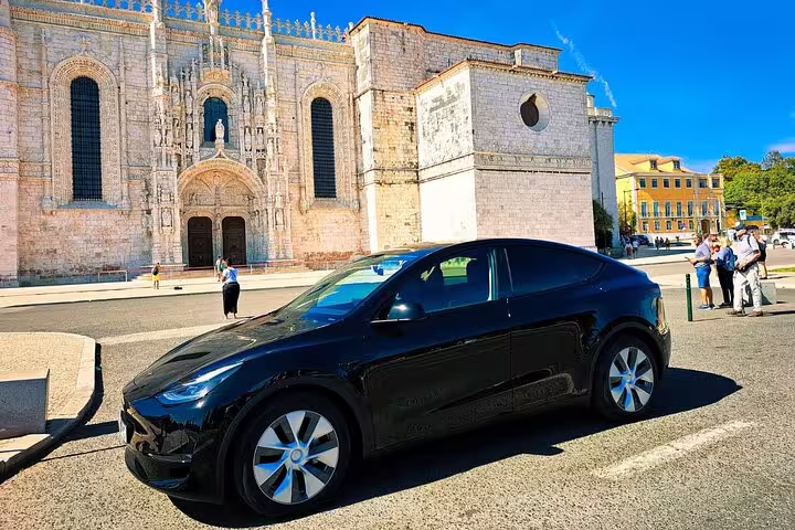 Sleek black car parked near Lisbon's historic Jerónimos Monastery, highlighting private journey from Algarve to Lisbon.
