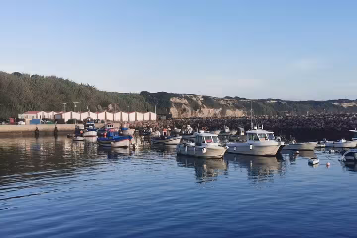Coastal fishing harbor stop on Algarve to Lisbon private transfer, small boats on calm Atlantic water