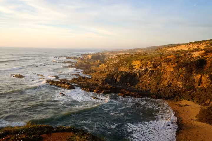 Golden-hour view of wild coastline and beach, scenic stop on Algarve to Lisbon private transfer tour