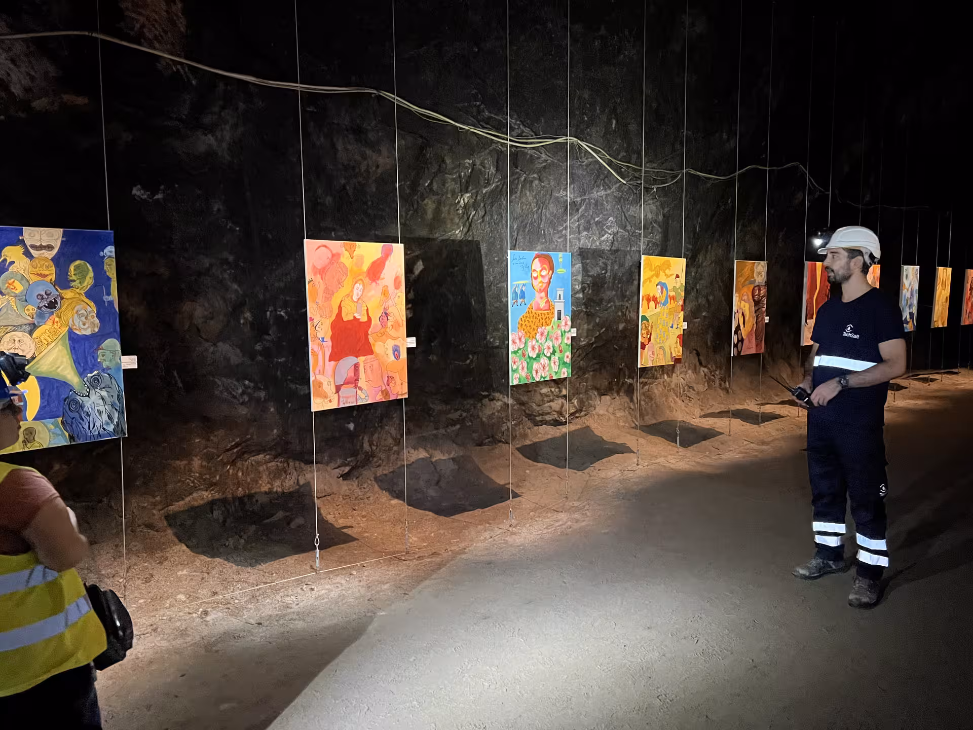Visitors admire vibrant paintings on display in the illuminated Loulé rocksalt mine during a guided Algarve tour.