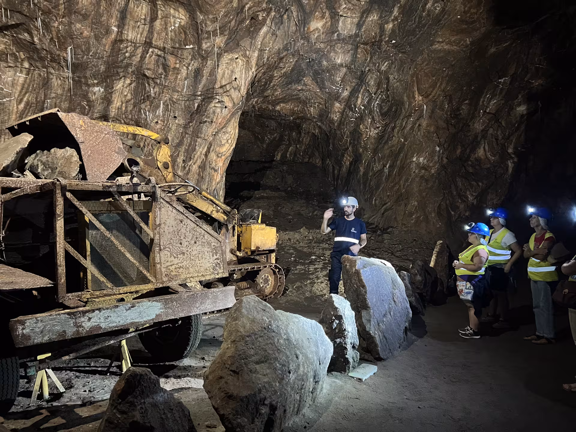 Tour group listens to guide near machinery inside Loulé rocksalt mine, exploring Algarve’s geological wonders.