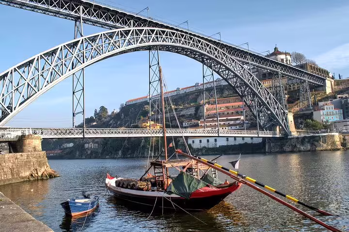 Traditional boat docked under the iconic Dom Luís I Bridge in Porto, perfect for Algarve to Porto scenic tours.