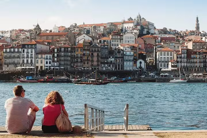Couple enjoying a riverside view of Porto's colorful historic district, a highlight of the Algarve to Porto journey.