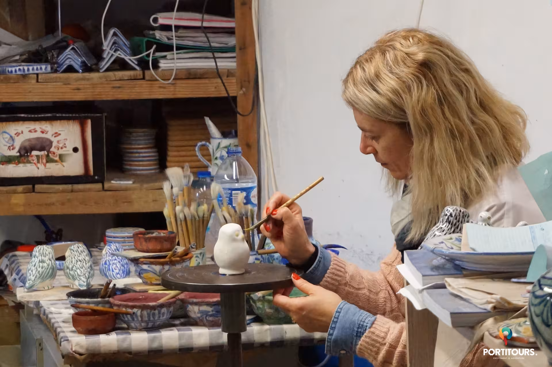 Artisan painting a ceramic bird by hand in an Algarve pottery studio, part of a cultural panoramic and wine tasting tour