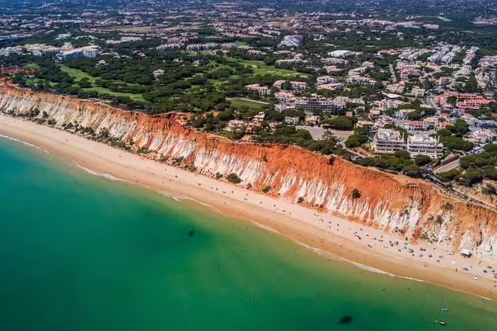 Aerial view of Algarve's stunning red cliffs and golden beach, perfect for a private tour experience in Portugal's scenic coastline.