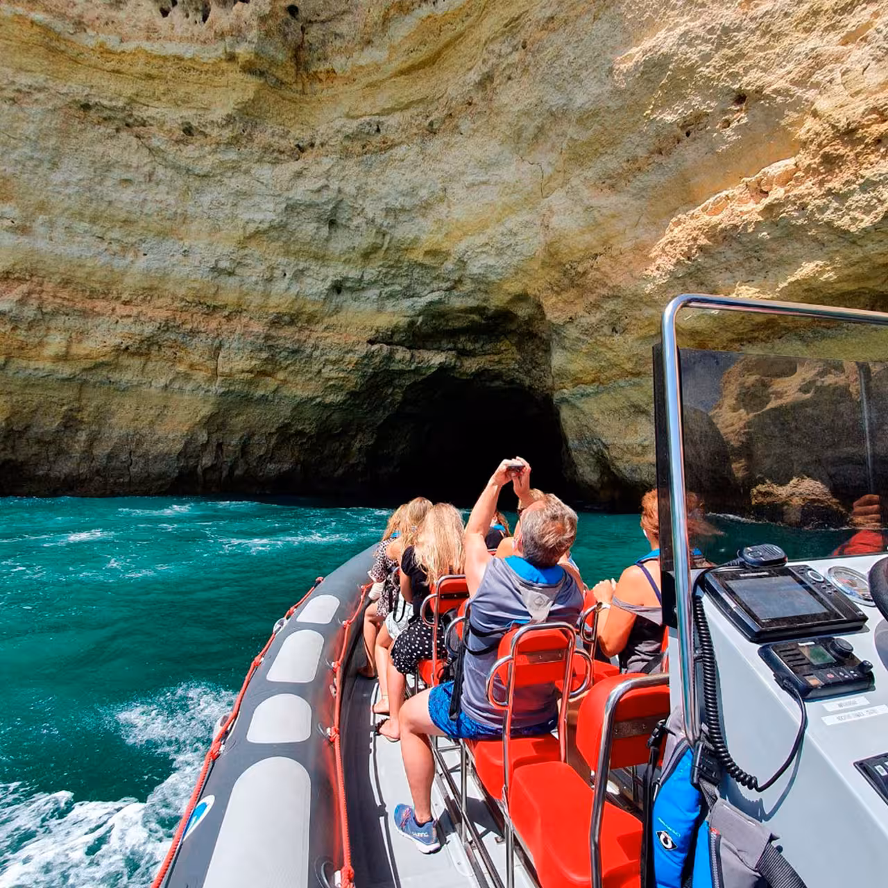 Passengers on RIB entering Algarve sea cave, exploring grottoes on Caves and Dolphins speedboat tour
