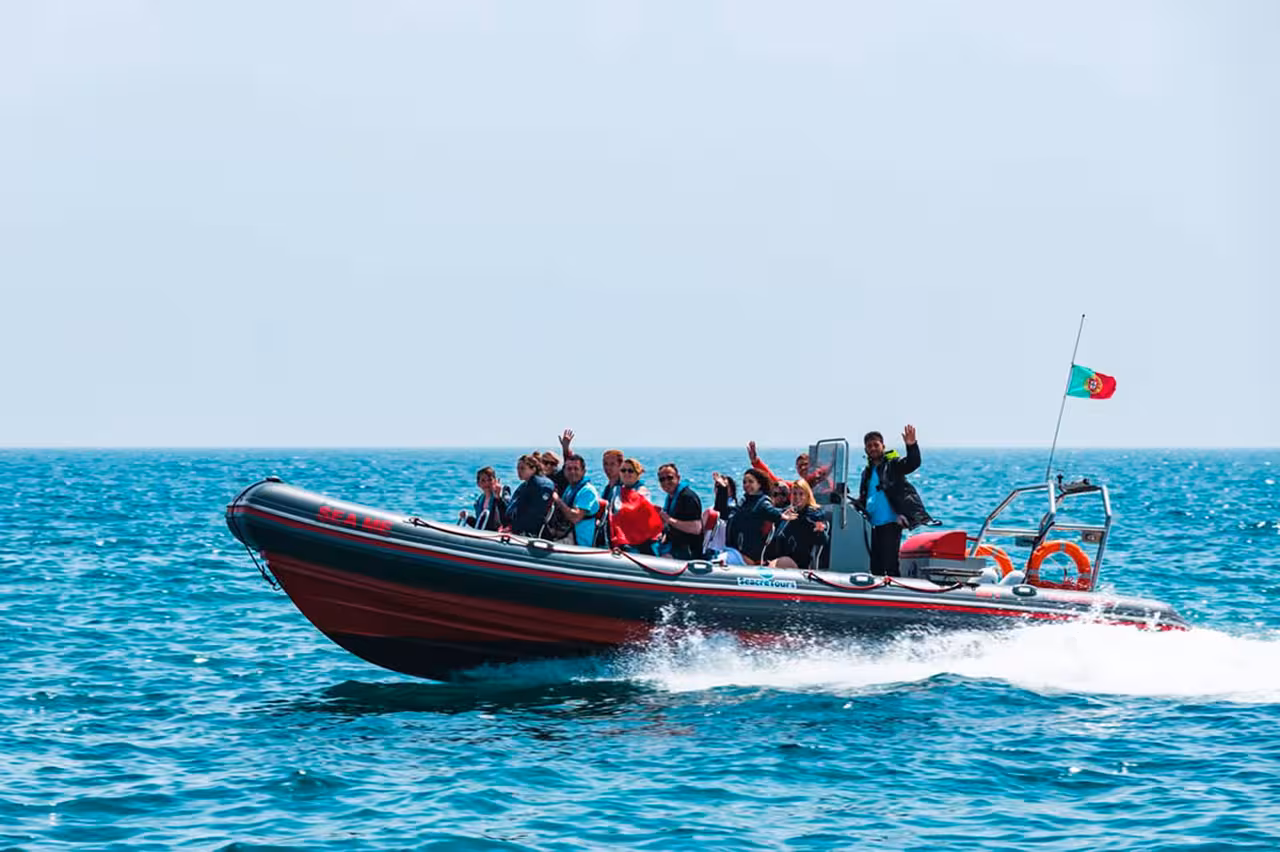 RIB speedboat with guests on Algarve Caves and Dolphins tour, cruising the Atlantic coastline for wildlife