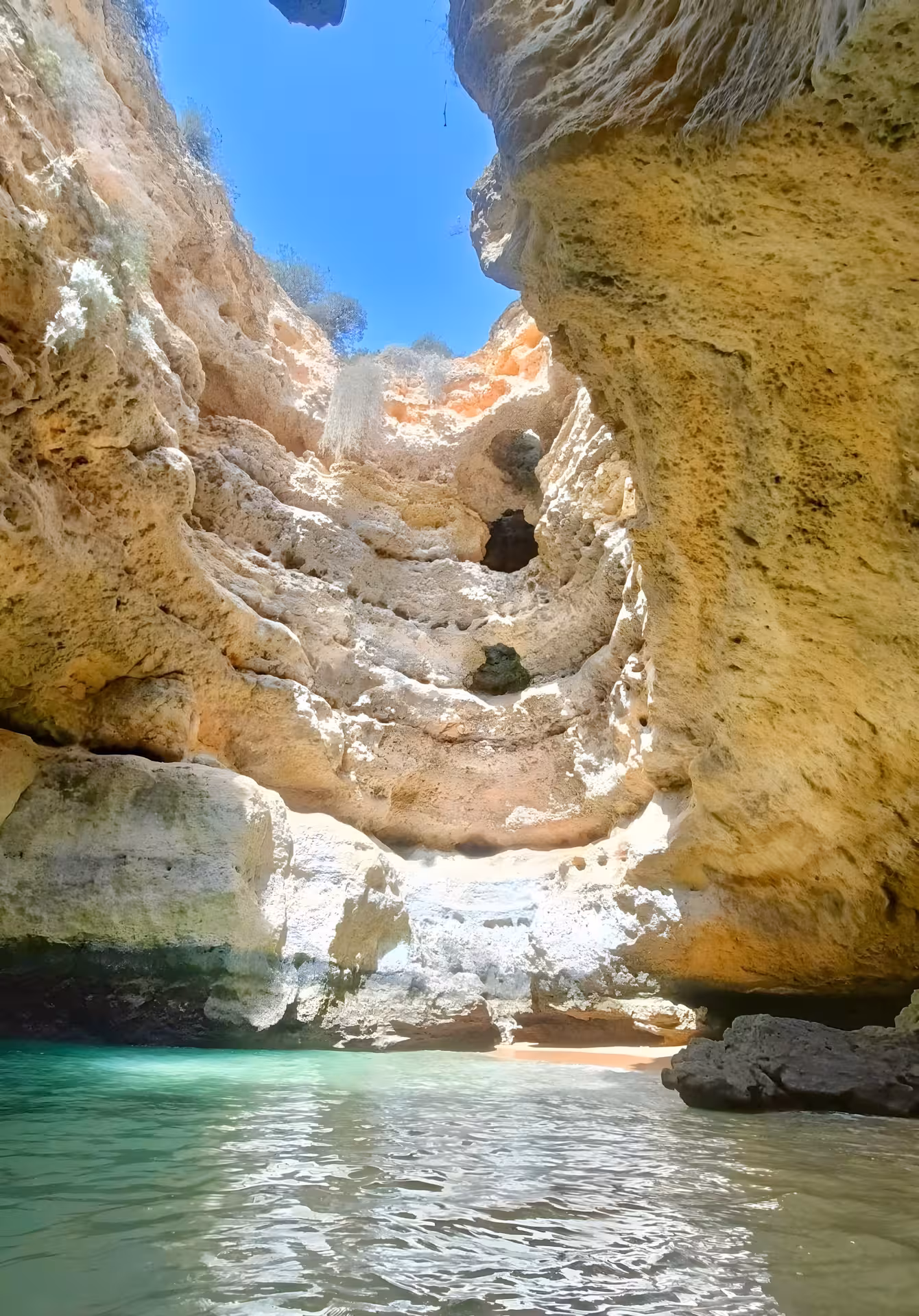 Crystal-clear water and sunlit rock walls inside a secluded Algarve sea cave, visited on a coastal caves boat tour
