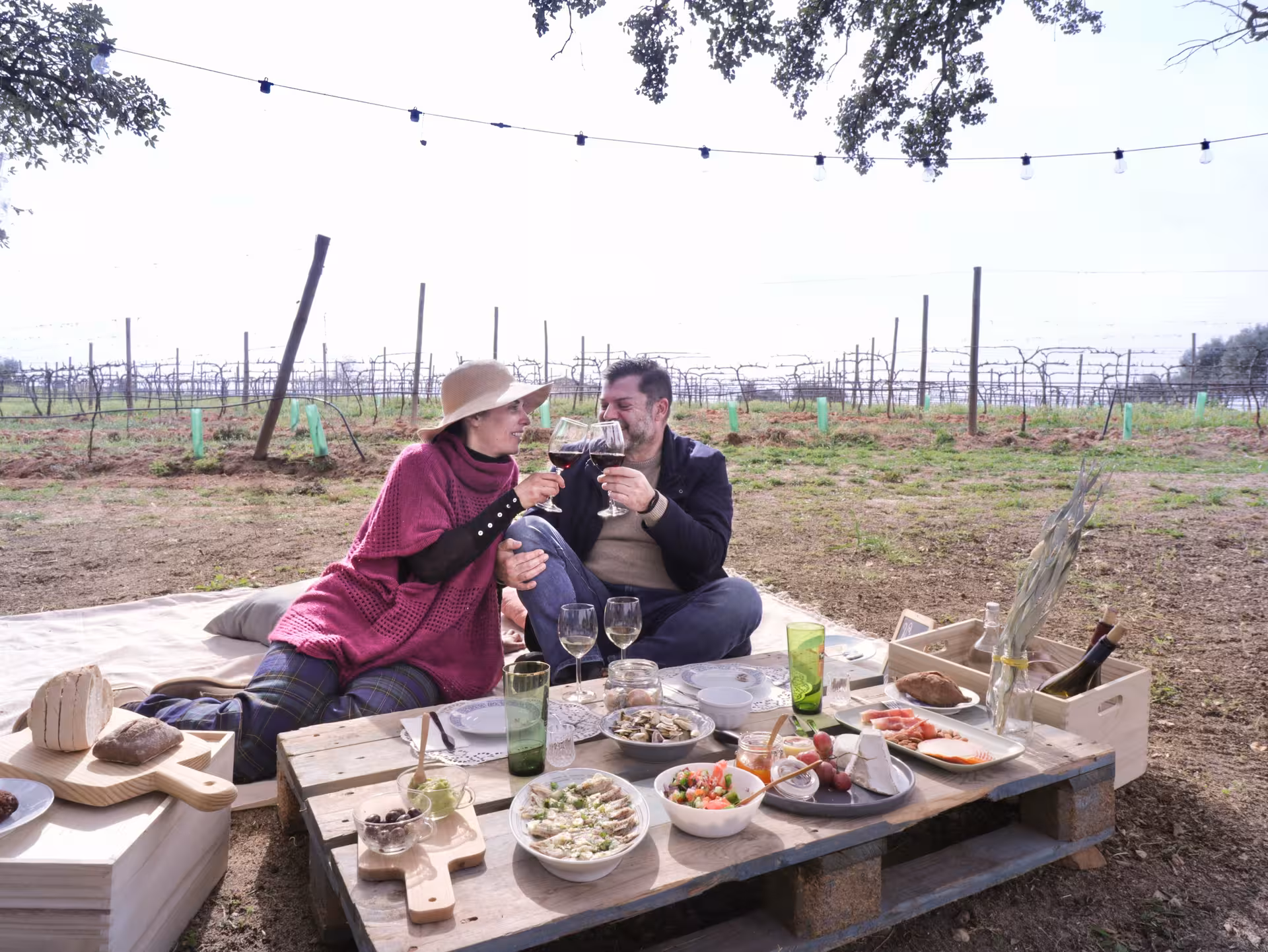 Couple enjoying wine and gourmet snacks on a private Algarve vineyard tour, surrounded by lush vineyard scenery.
