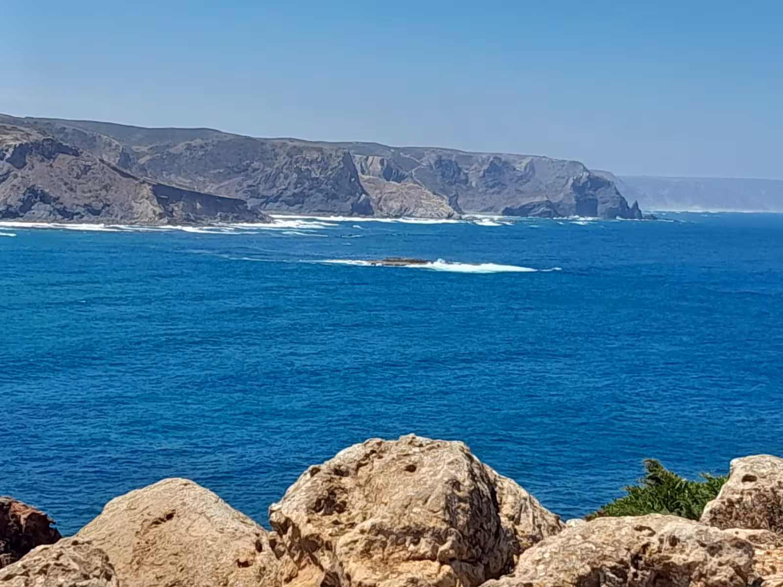 Rocky cliffs and deep blue Atlantic waves along the wild Algarve West Coast, seen on a full day scenic tour in Portugal