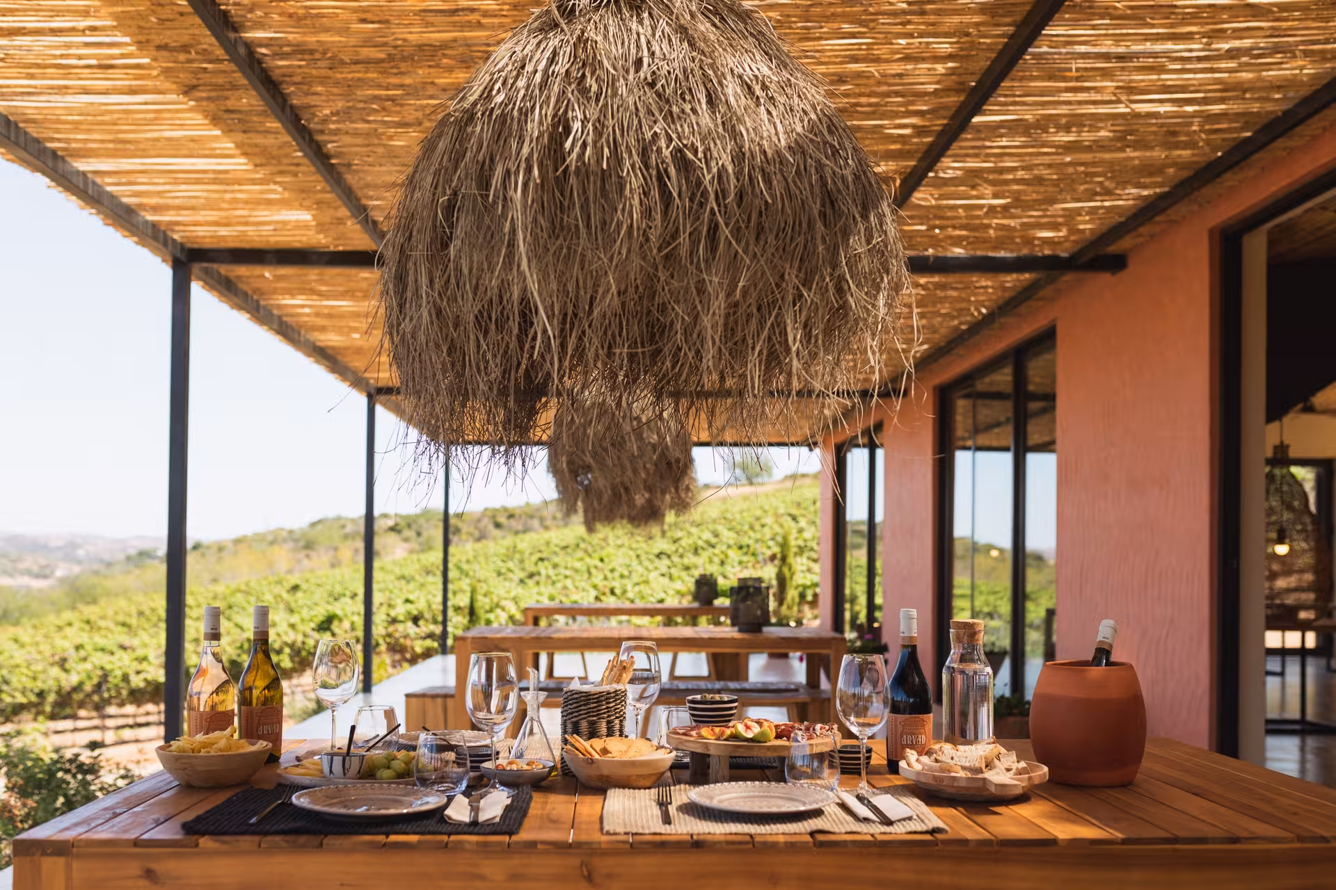 Outdoor wine tasting table at Arvad Winery in Algarve, set with bottles, tapas and vineyard views under a rustic pergola