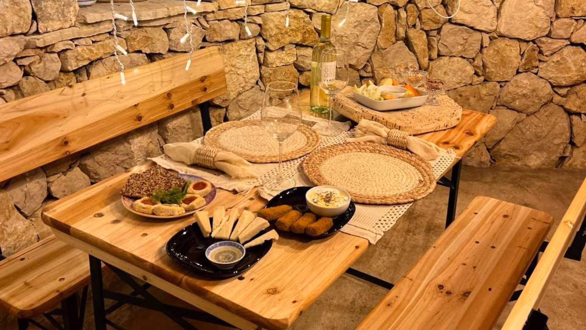 Rustic dining setup with assorted appetizers and white wine in Alghero animal shelter tour experience.