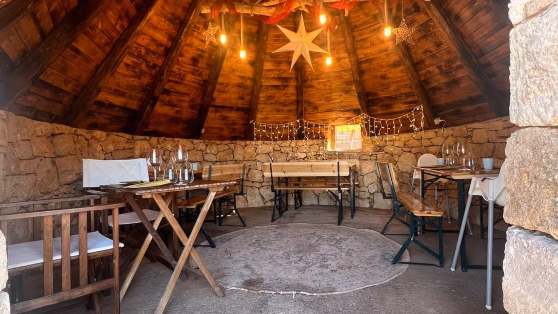 Cozy dining area with rustic stone walls and wooden decor at an Alghero animal shelter, ideal for lunch or dinner.