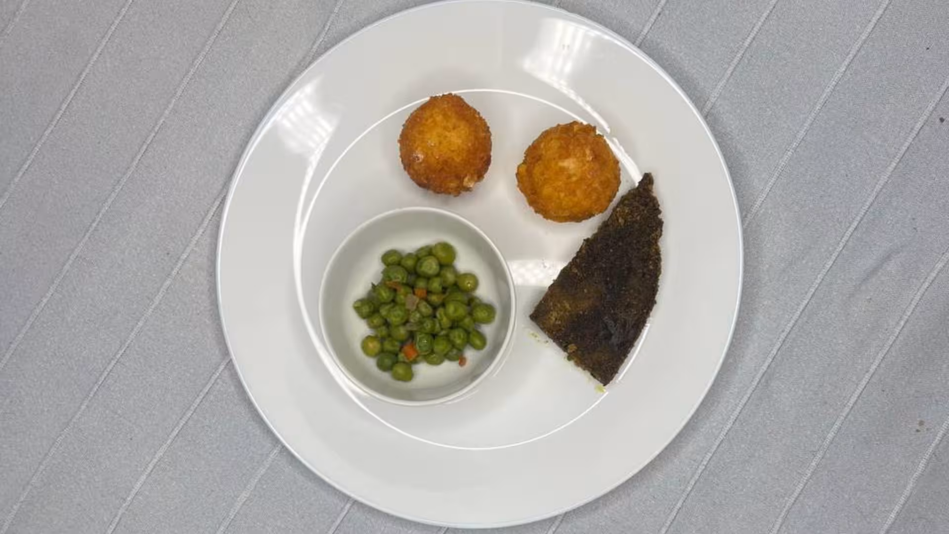 Plate with fried balls, peas, and a slice of cake in Alghero animal shelter lunch or dinner offering.