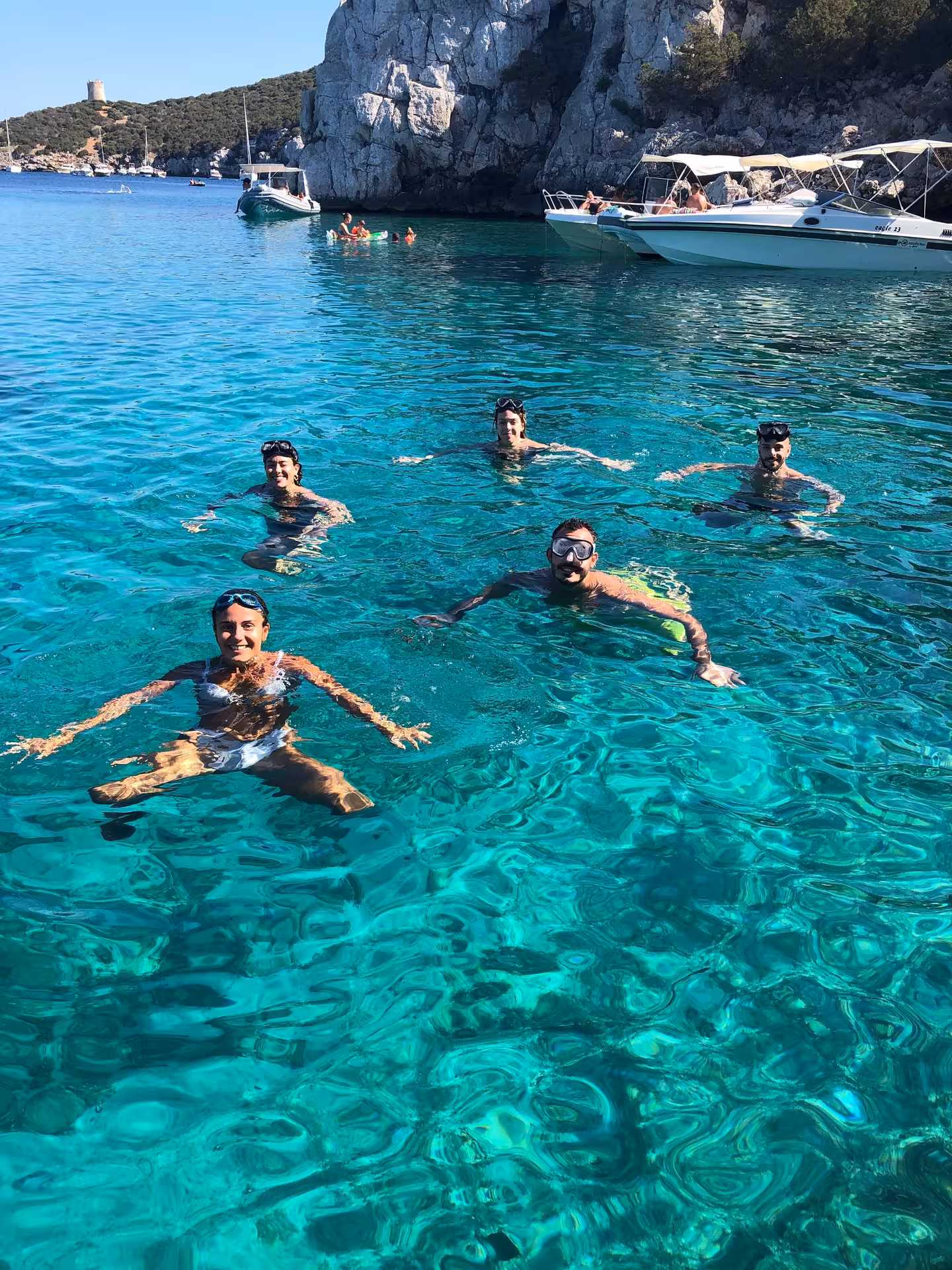 Group enjoying snorkeling in crystal-clear waters near Capo Caccia on an Alghero dinghy tour.