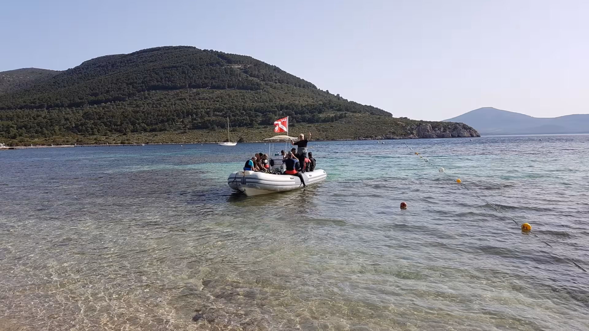 Tourists on a boat with a dive flag near Alghero, preparing for a beginner discovery diving lesson in scenic waters.
