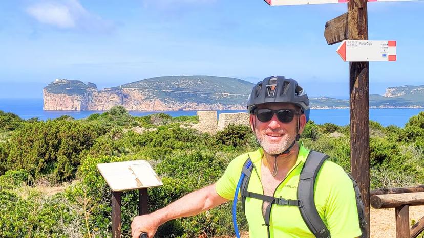 Cyclist enjoying panoramic view of Capo Caccia coastline on guided ebike tour in Alghero.