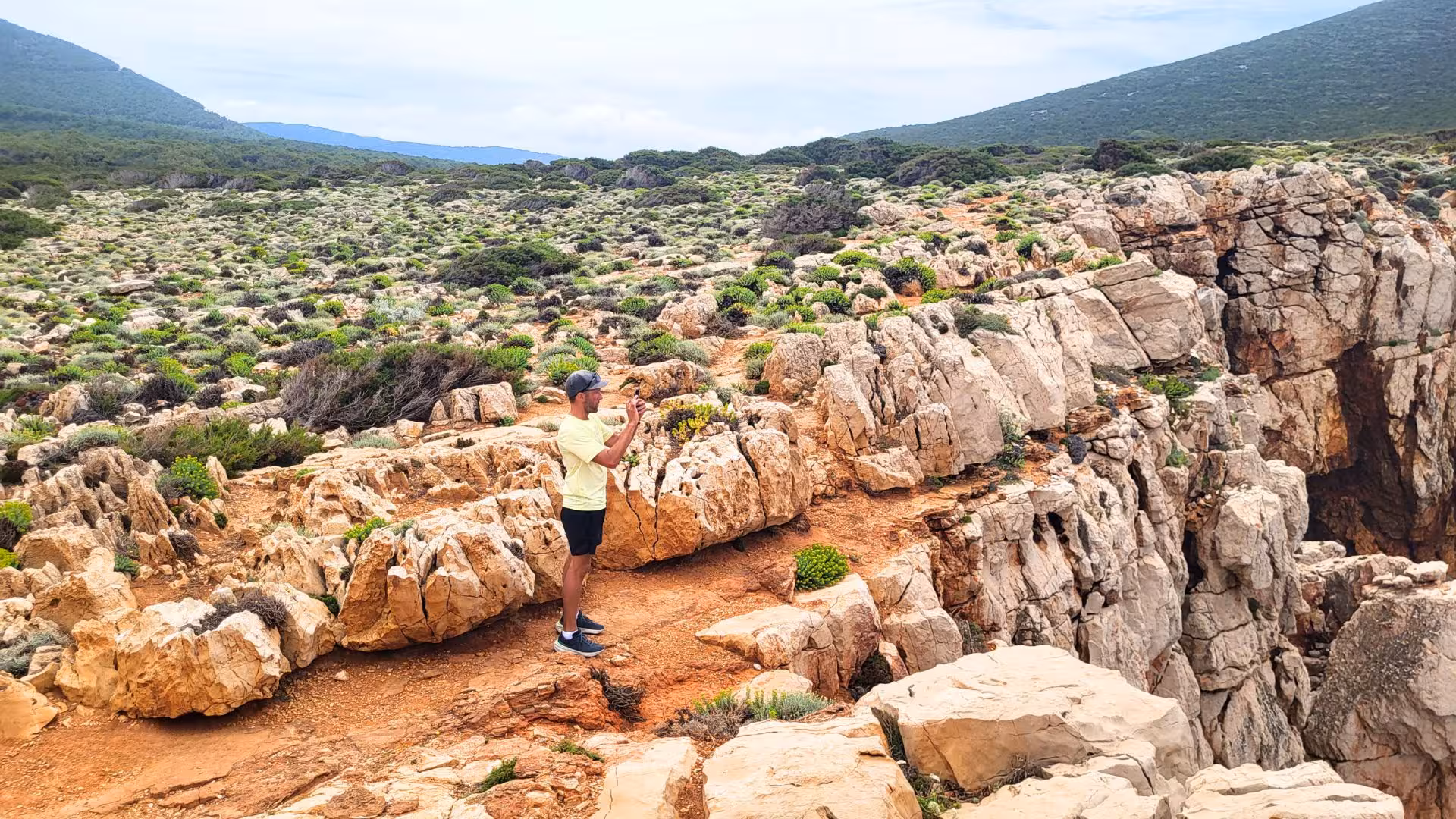 Visitor photographing the rugged rocky landscape of Capo Caccia on an Alghero guided e-bike tour.