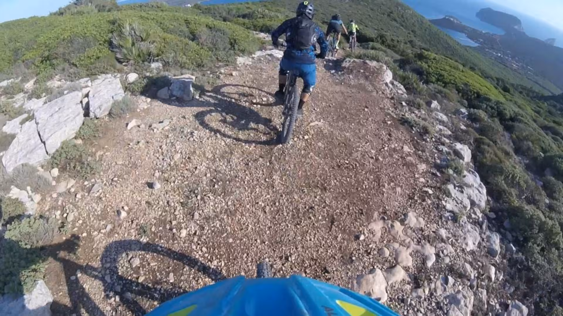 Group of cyclists navigating rocky trails with coastal views in Porto Conte Park, Alghero e-bike tour.