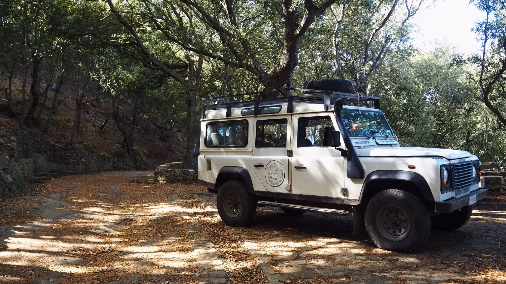Off-road vehicle parked in a shaded forest area near Porto Ferro, ideal for adventurous tours from Alghero.