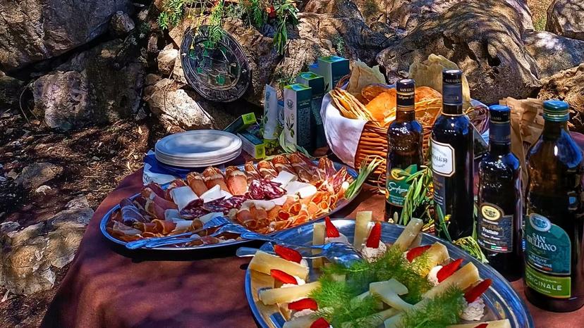 Close-up of a gourmet olive oil tasting spread with cheeses, meats, and bread in Alghero's olive grove.