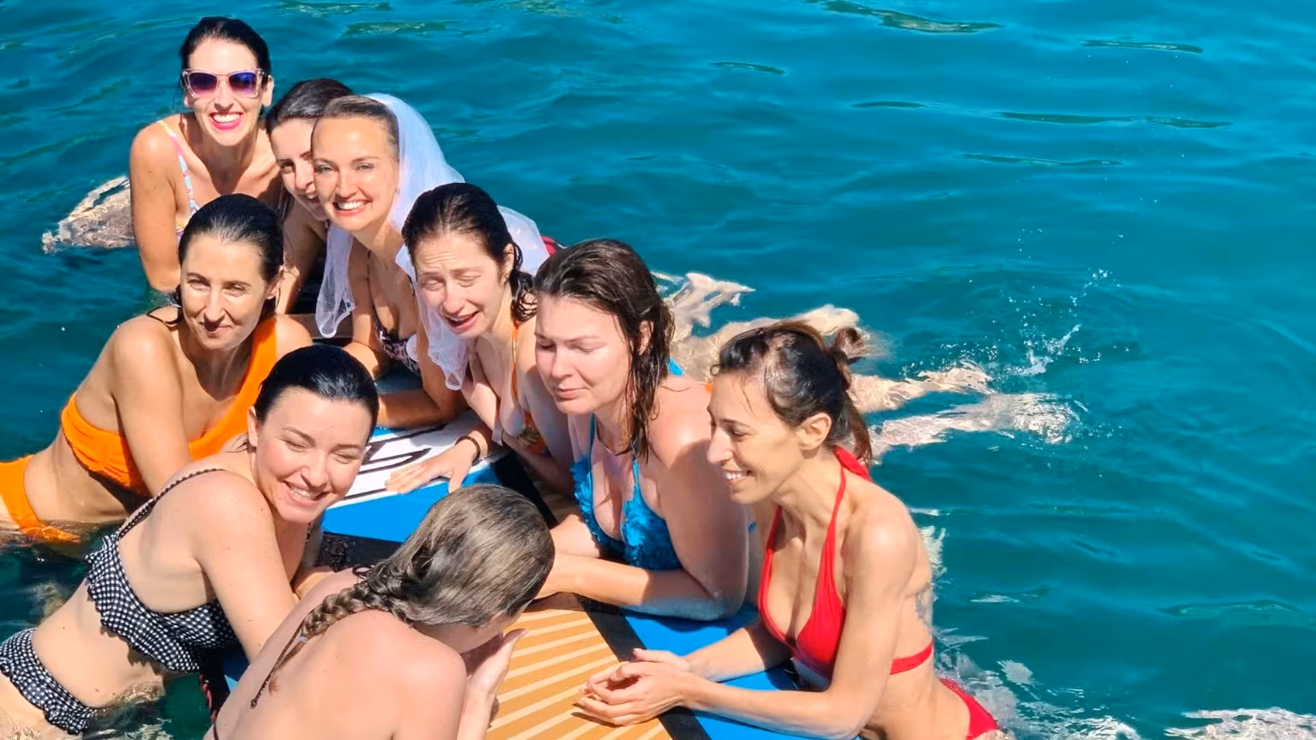 Group of women enjoying a swim during Alghero Porto Conte Park sailing tour under sunny skies.