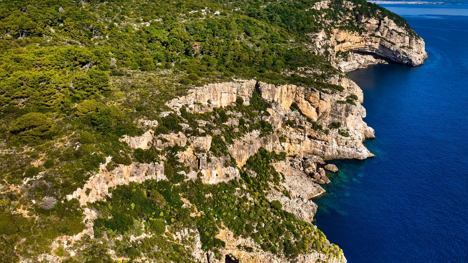 Scenic view of rugged cliffs and turquoise waters at Porto Conte Park, perfect for trekking near Alghero, Sardinia.