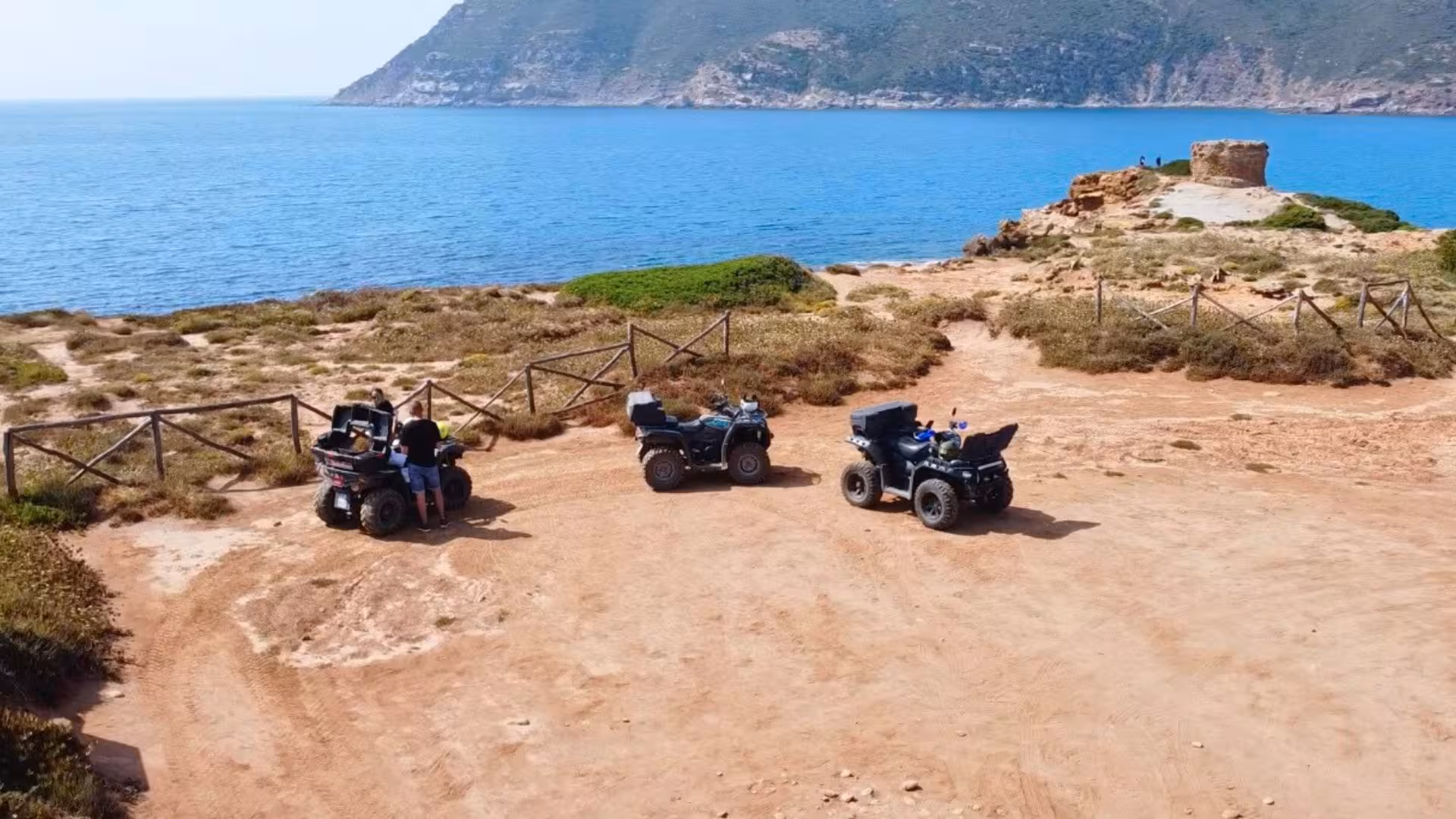 Three quad bikes parked by the Alghero coastline, ready for an adventurous 4-hour quad tour with stunning sea views.