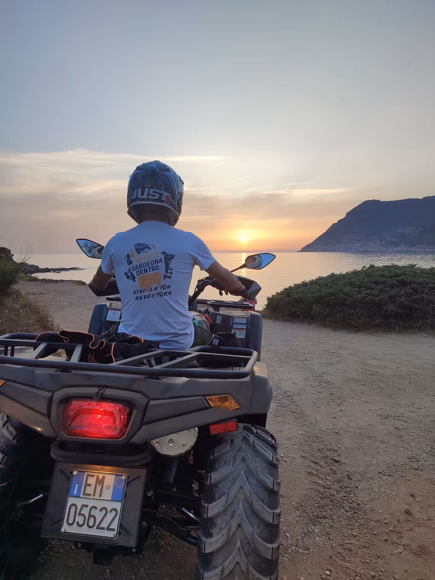 Quad rider overlooking a stunning Alghero sunset by the sea, capturing the essence of adventure and scenic beauty.