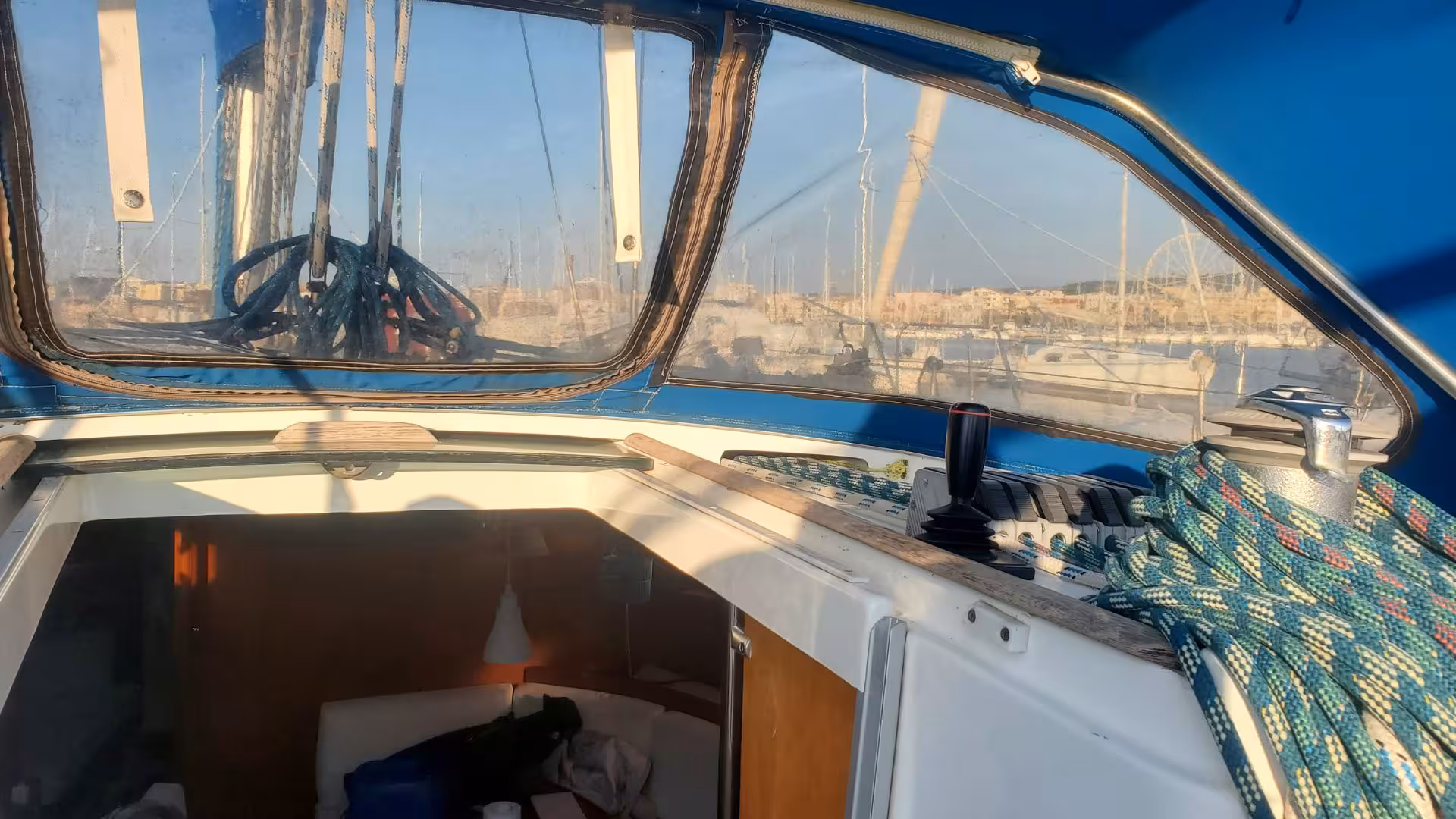 View of a sailboat cockpit with ropes and sunlight in Alghero, perfect for a relaxing day on the water.