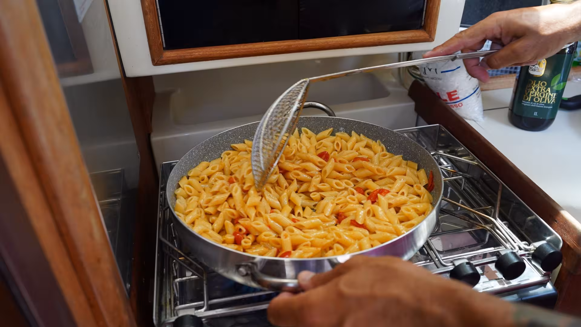 Delicious Italian pasta being prepared on a boat kitchen during Alghero sailing tour in Porto Conte Park.