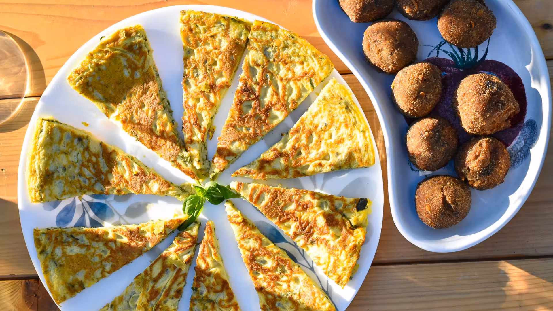 Sardinian frittata and meatballs served on a wooden table under the sun in Alghero vineyard tour.