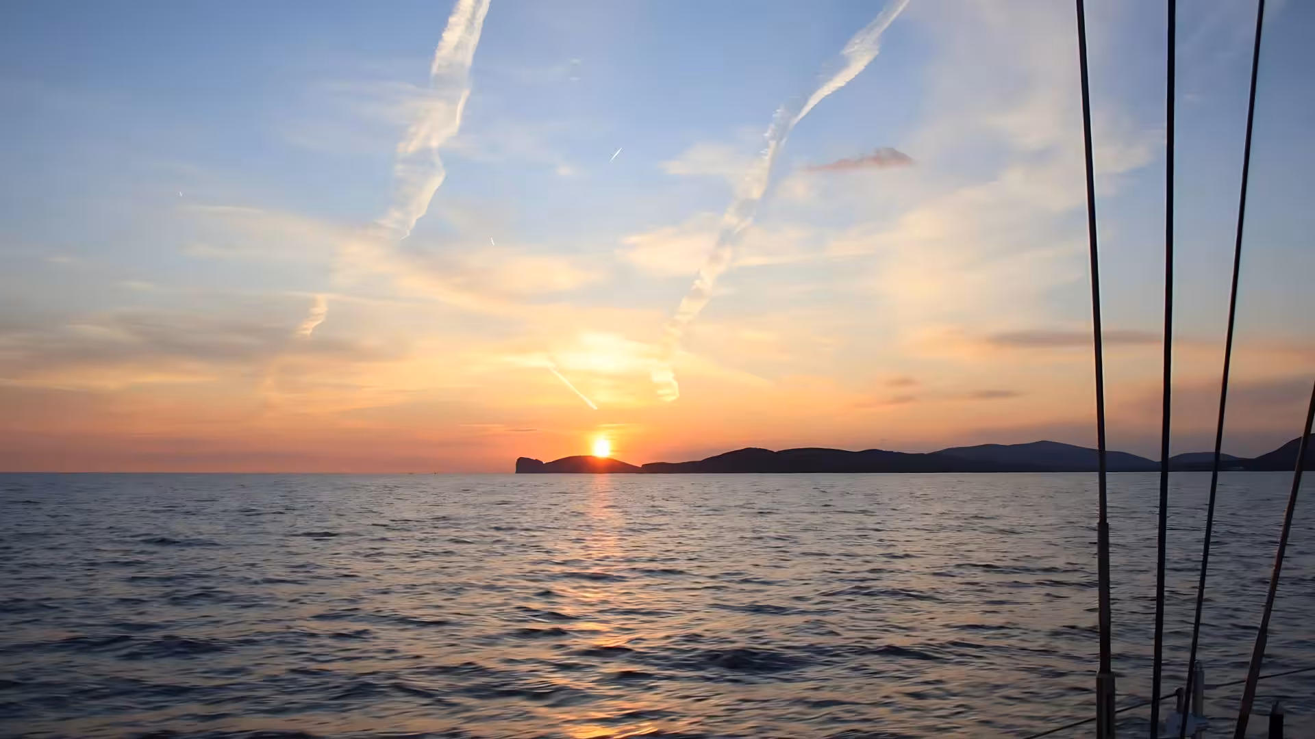 Breathtaking sunset view over the sea from a sailing boat near Alghero, perfect for a romantic aperitif experience.