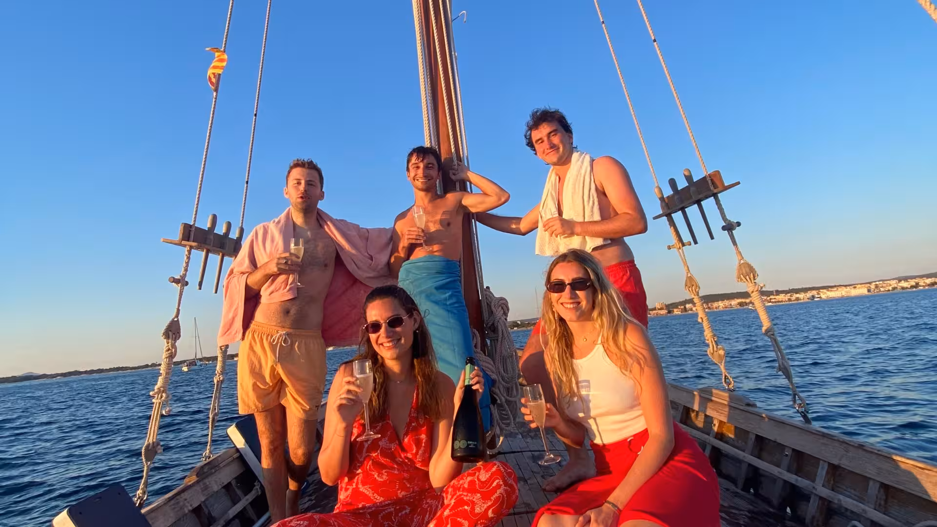 Group of friends enjoying aperitifs on a sunset sailing tour in Alghero, Sardinia.