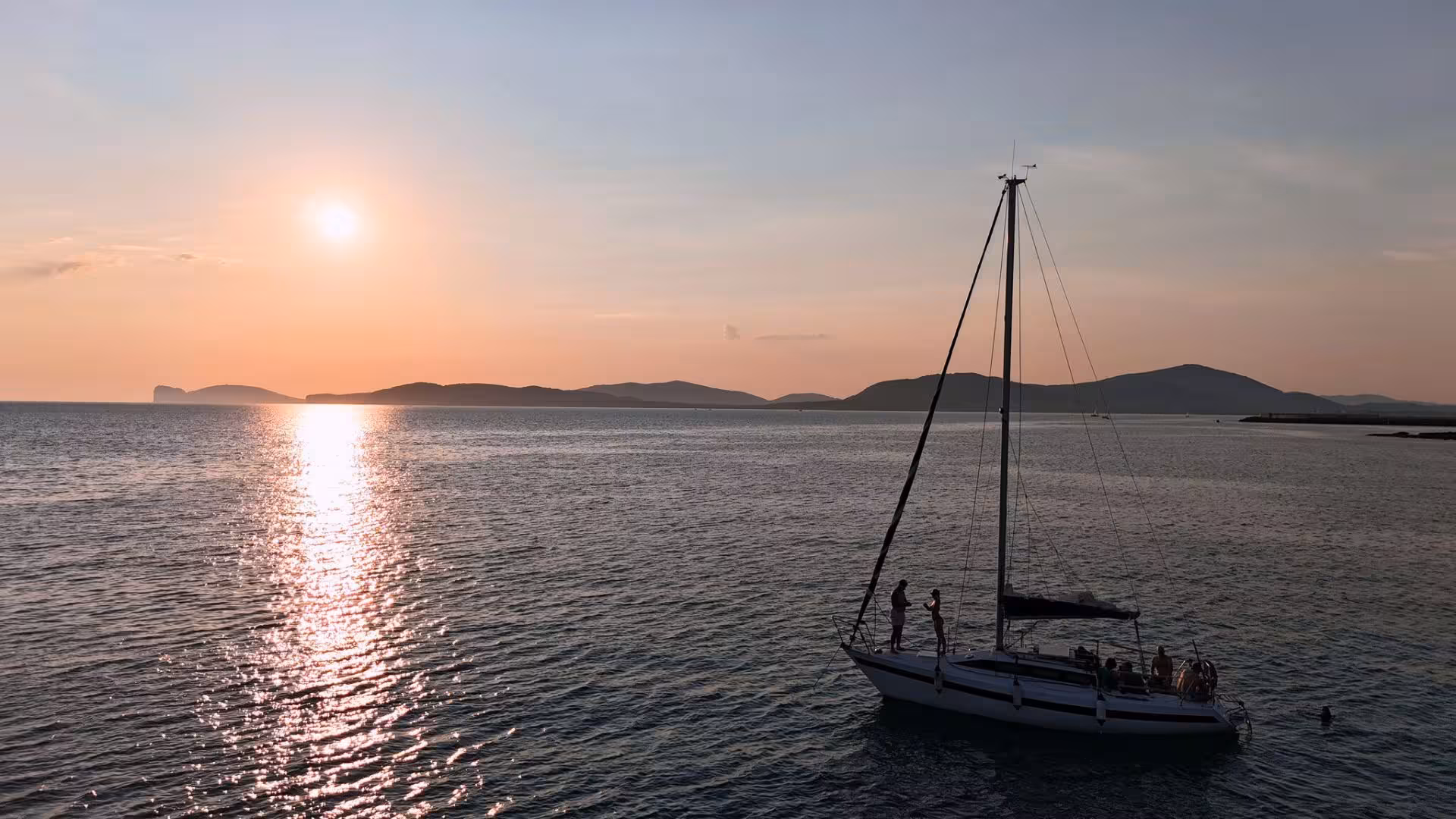Sailboat cruising during picturesque Alghero sunset tour from Fertilia with scenic horizon view.