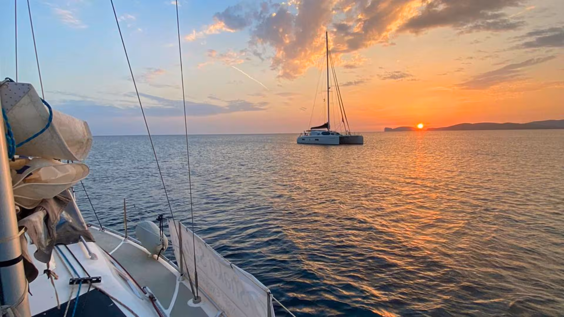 Sailboat on calm waters with a stunning sunset backdrop on the Alghero sunset sailing tour.