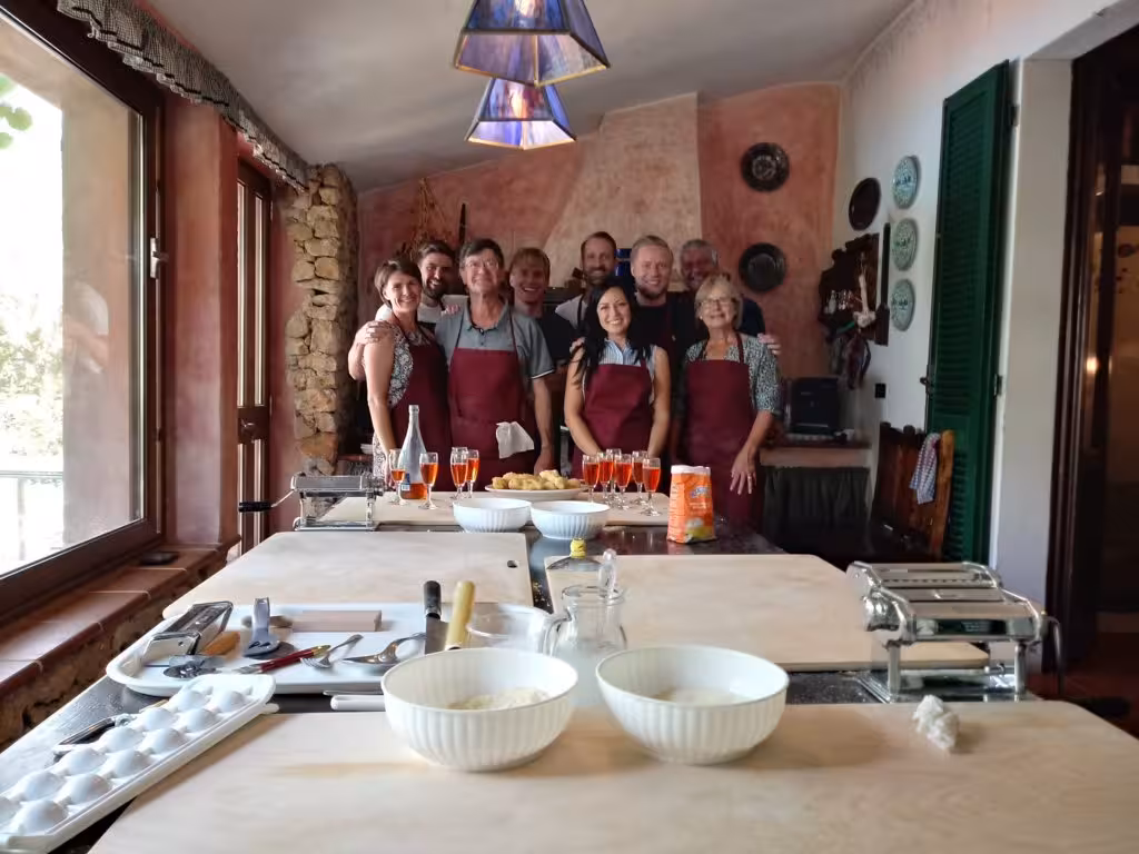 Group of happy participants in aprons enjoying a traditional cooking class in Olmedo, Alghero.
