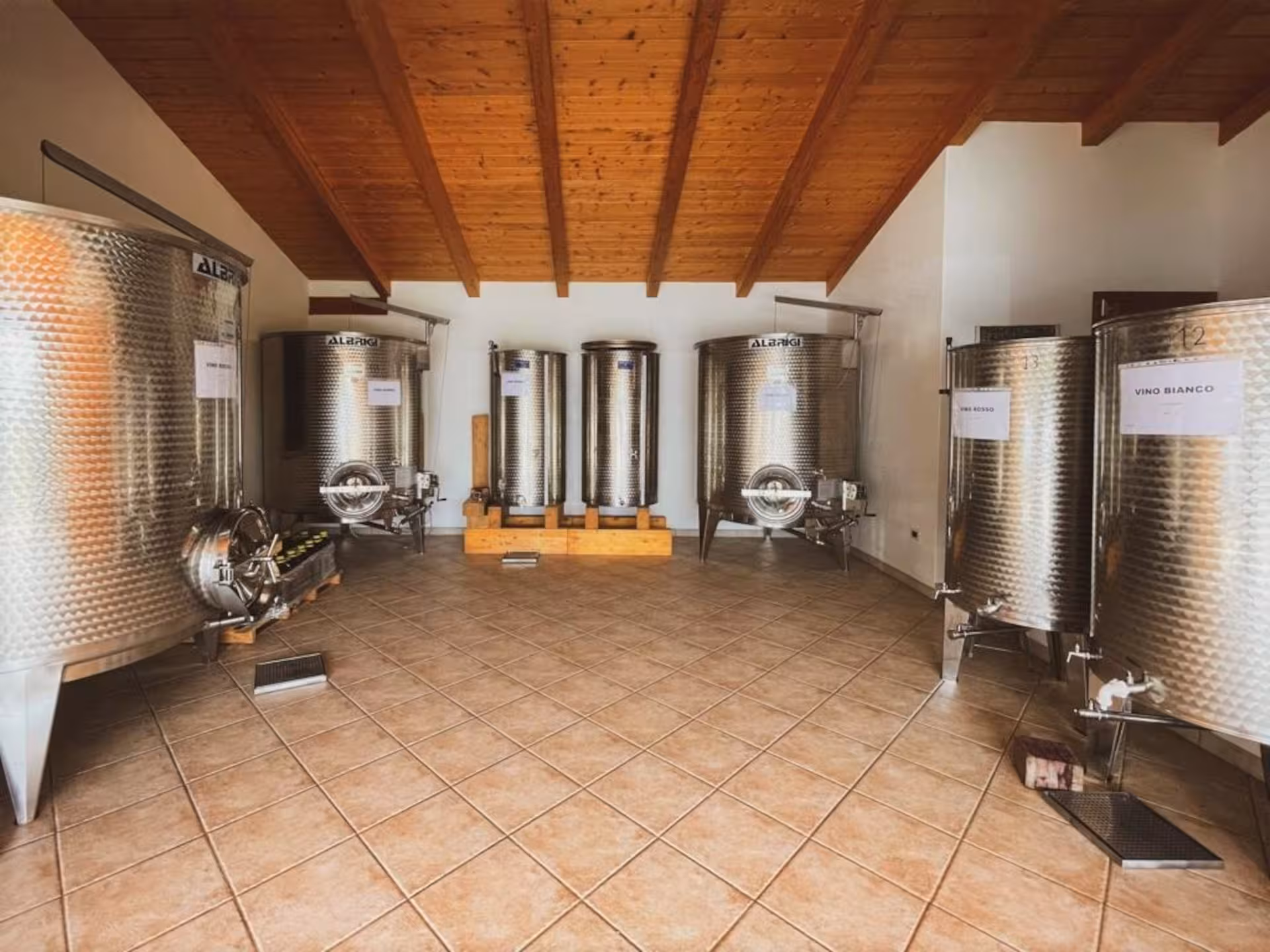 Interior of a winery with stainless steel fermentation tanks in Alghero, highlighting the wine-making process.