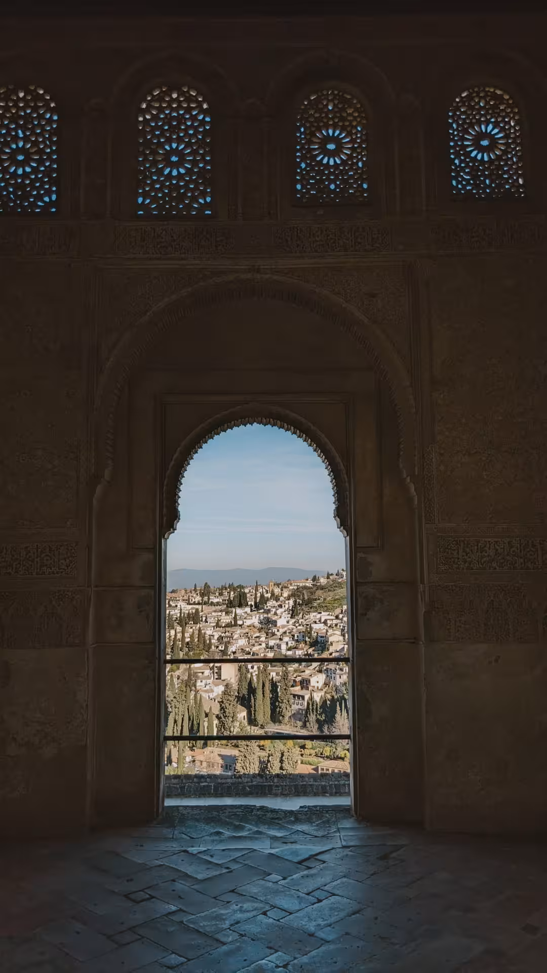 Scenic view of Albaicín from a decorative arch in the Alhambra, capturing the essence of Granada's history.