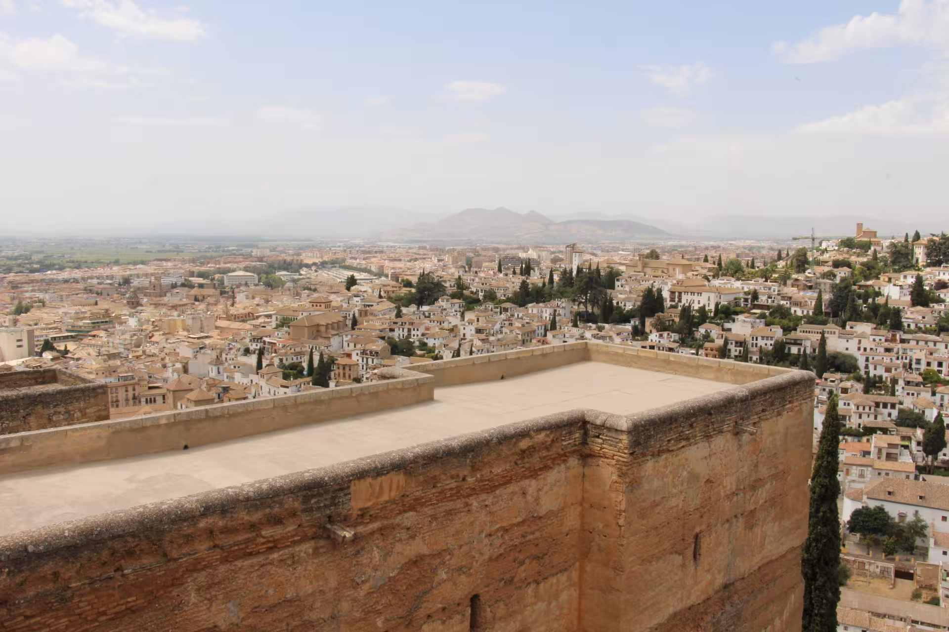 Panoramic view of Granada from the Alhambra, showcasing historic architecture and distant mountains.