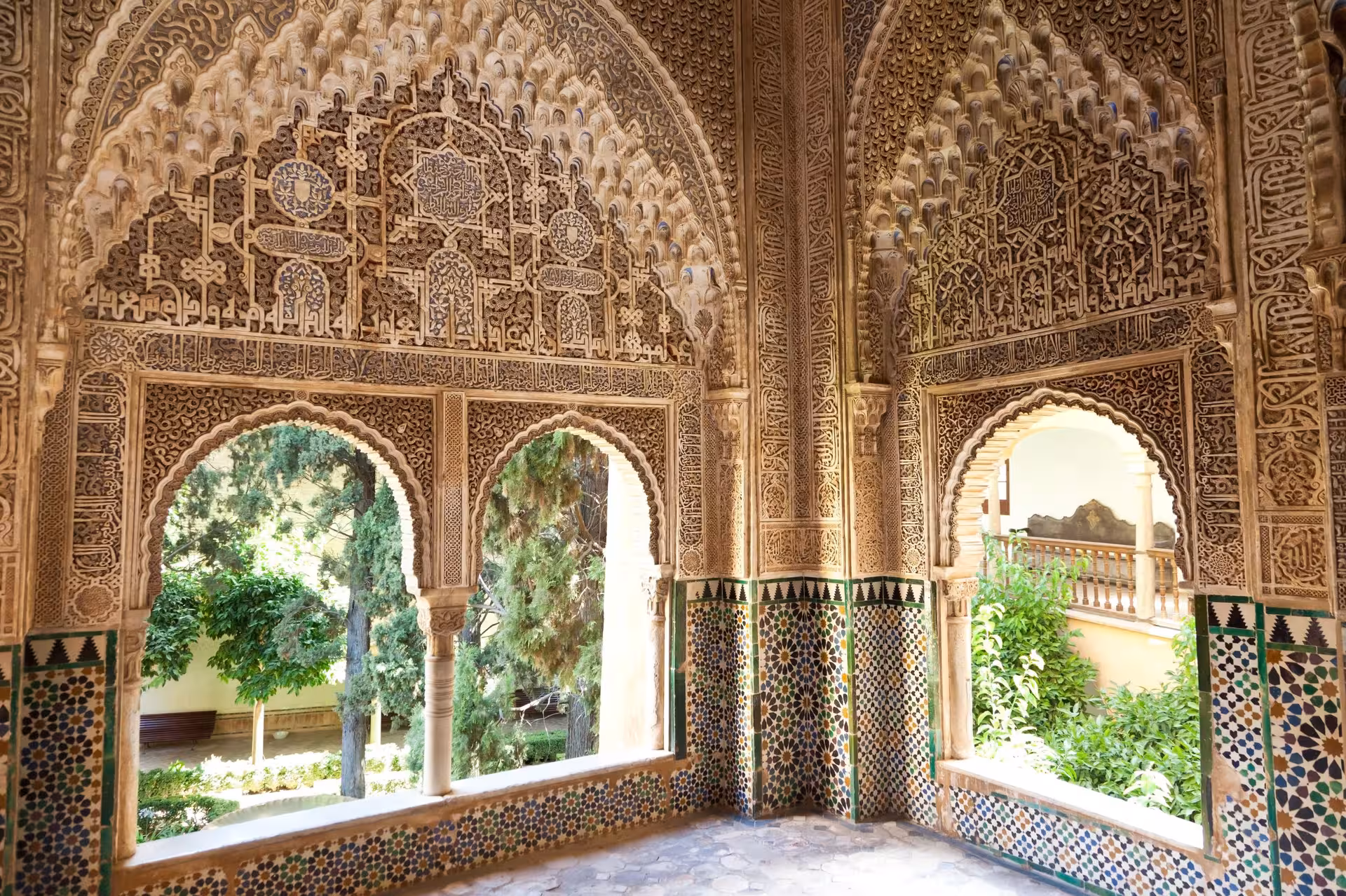 Intricate Moorish architecture inside Alhambra's Nasrid Palaces, featuring ornate arches and lush gardens.